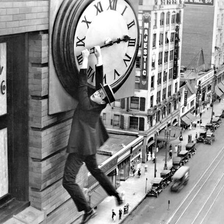 Schwarz-Weiss Foto mit einem Mann, der an einer Uhr in der Luft hängt.  | © Kultur am Pass